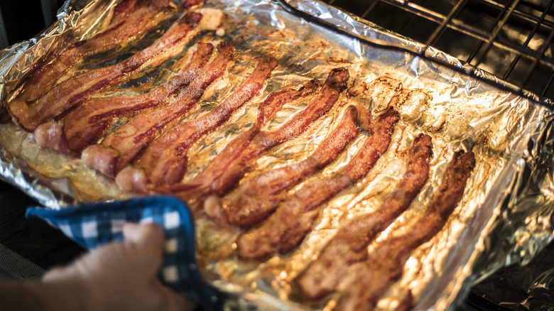 Person pulling pan of bacon out of oven