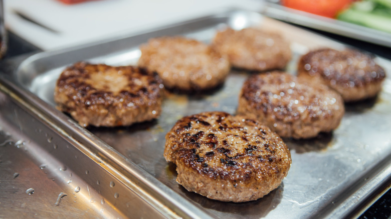 Beef burger patties on metal baking sheet