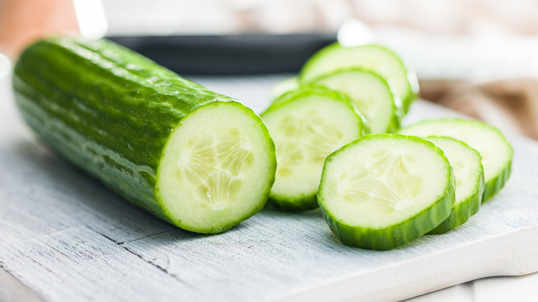 sliced cucumber resting on wooden cutting board