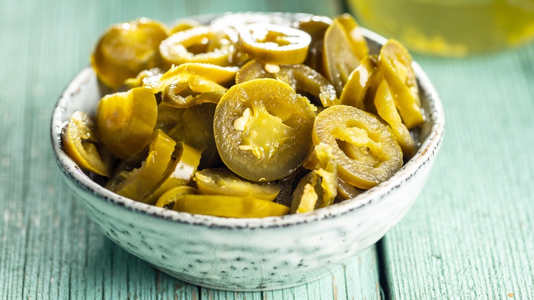 pickled jalapenos in a bowl on wooden counter