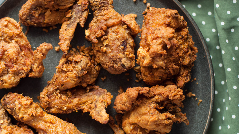 Pieces of fried chicken on a gray plate with a green polka dot cloth behind it