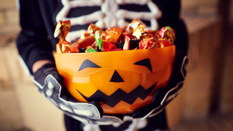 kid in skeleton costume holding Halloween candy 