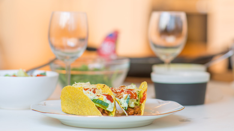 Plate of tacos with wine glasses in background