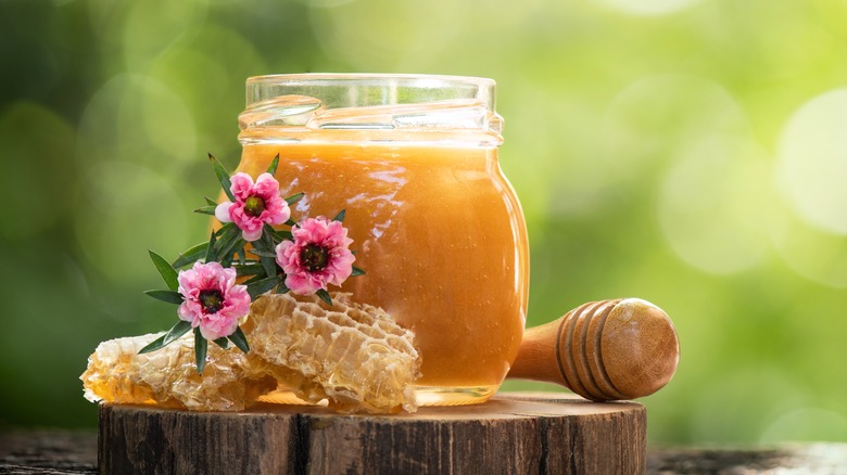 jar of raw honey next to flowers