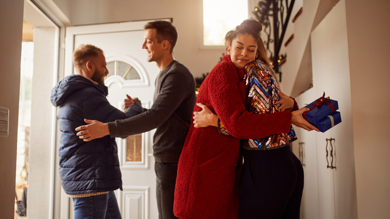 Hosts greeting guests with a small gift at the front door