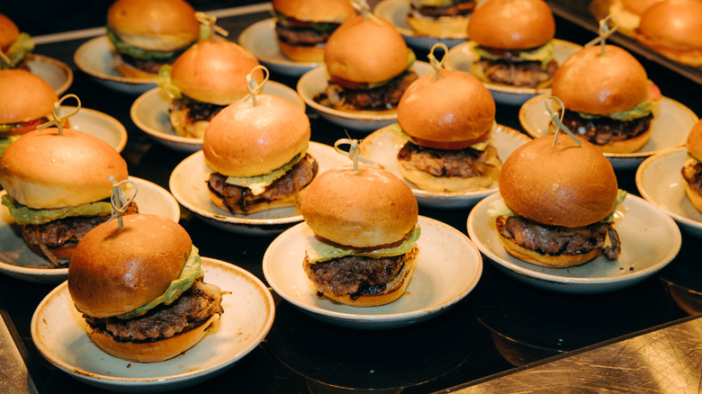 Burger sliders with lettuce lined up on small plates