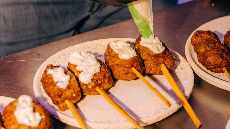 Piping sauce onto a fried food item on a stick