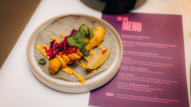 Fish taco on a gray plate with cabbage and cilantro