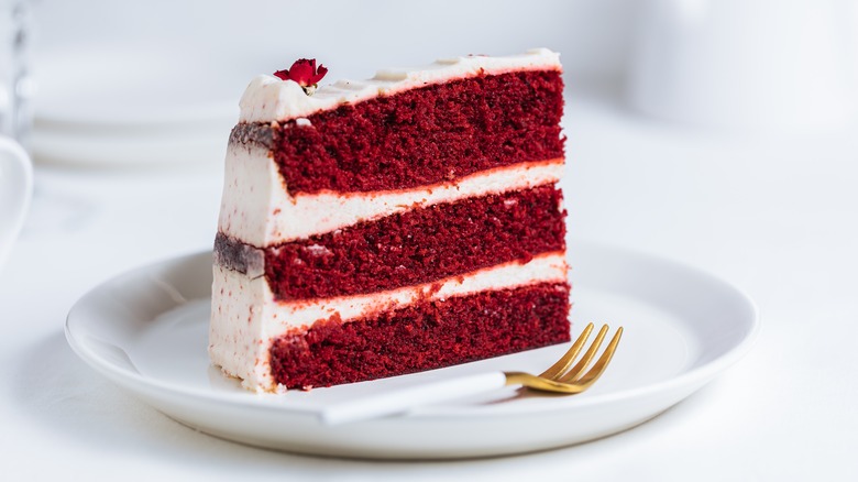 slice of triple layer red velvet cake with cream cheese frosting