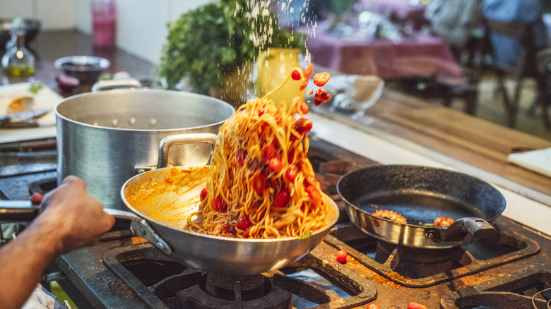 Tossing pasta and sauce together in pan