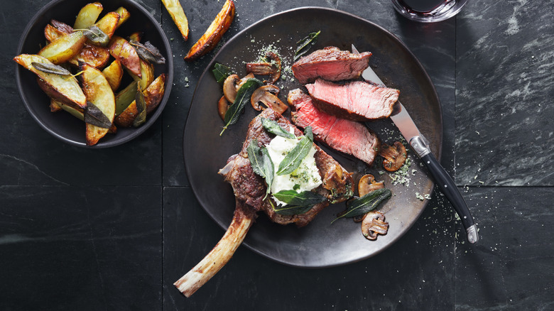 A cooked bone-in steak, served with some potato wedges