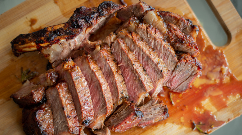 A steak on a wooden board with red liquid
