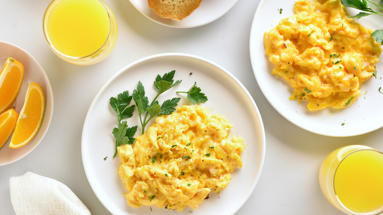 Plate of fluffy scrambled eggs with orange juice