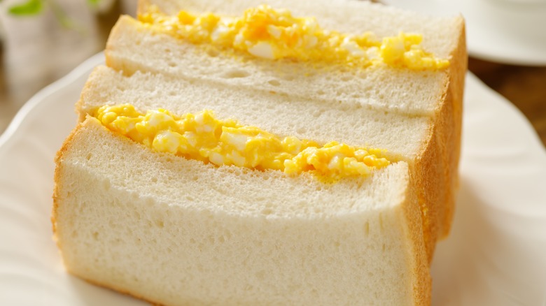 Halved egg salad sandwich on plate
