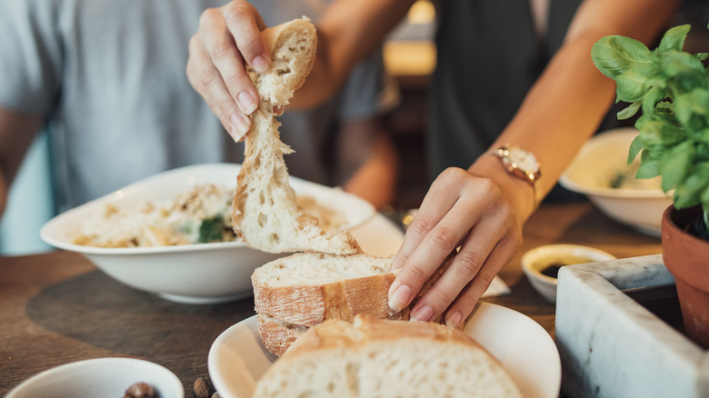 hands tearing off bread at restaurant