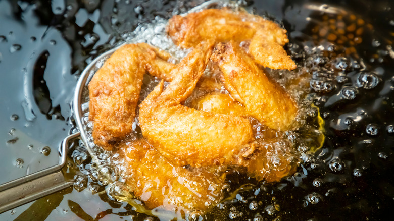 Chicken wings frying in oil.