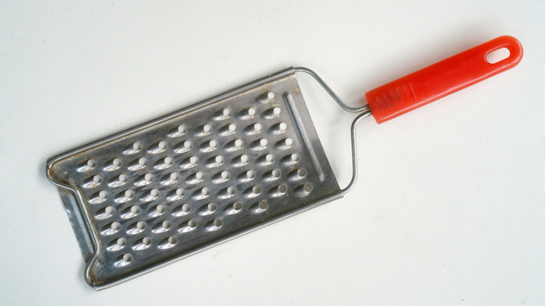 cheese grater with red handle on white background