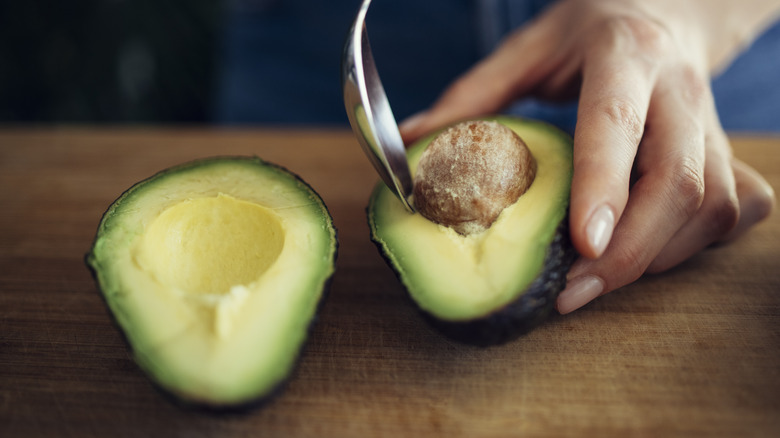 person taking pit out of avocado