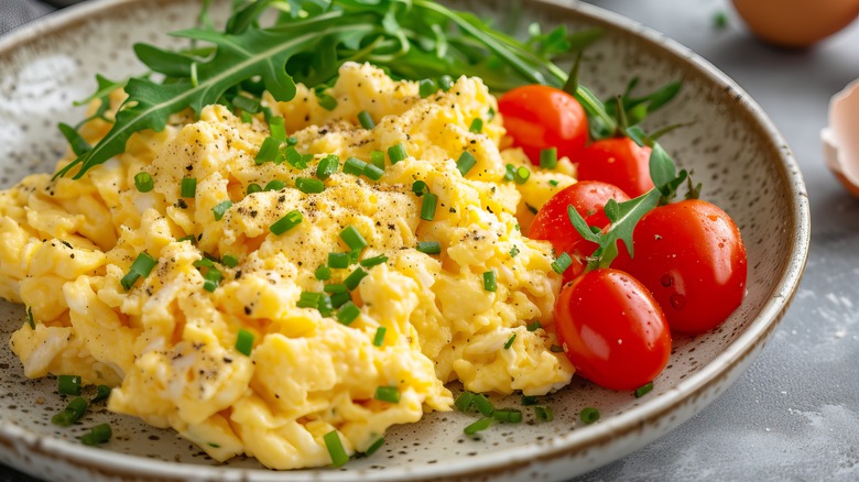 Scrambled eggs next to arugula and cherry tomatoes