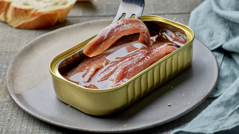 An open tin of anchovies on a plate