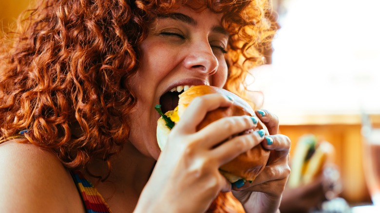 Person happily eating a hamburger with undefined patty