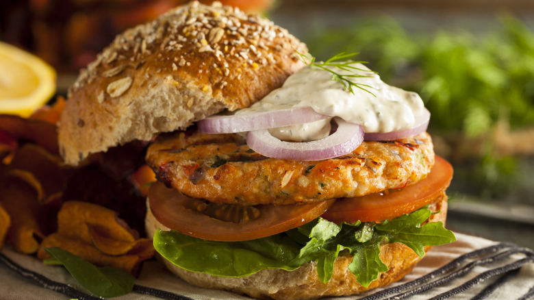 Salmon burger topped with tartar sauce and red onion