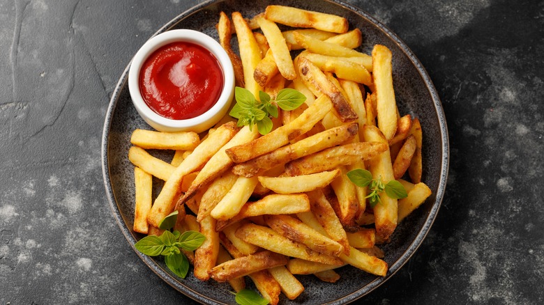 Crispy homemade french fries with ketchup and garnish in bowl