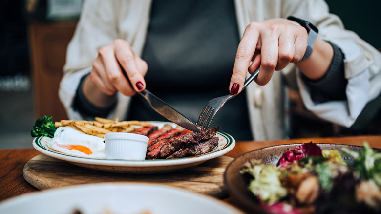 Someone cutting into a steak dinner at a restaurant