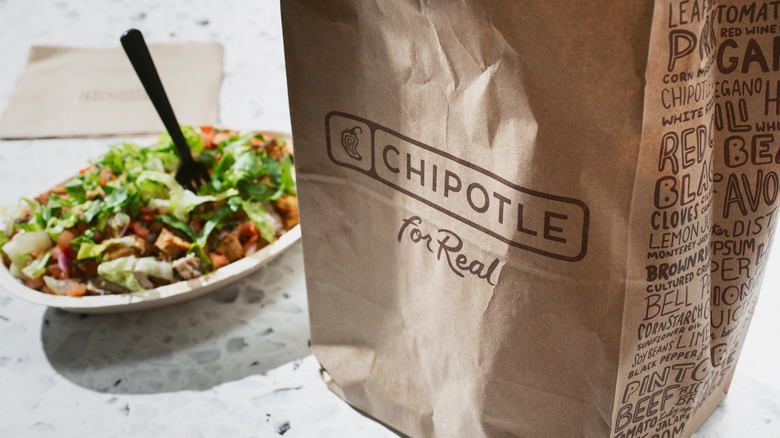 A brown chipotle bag next to a burrito box.