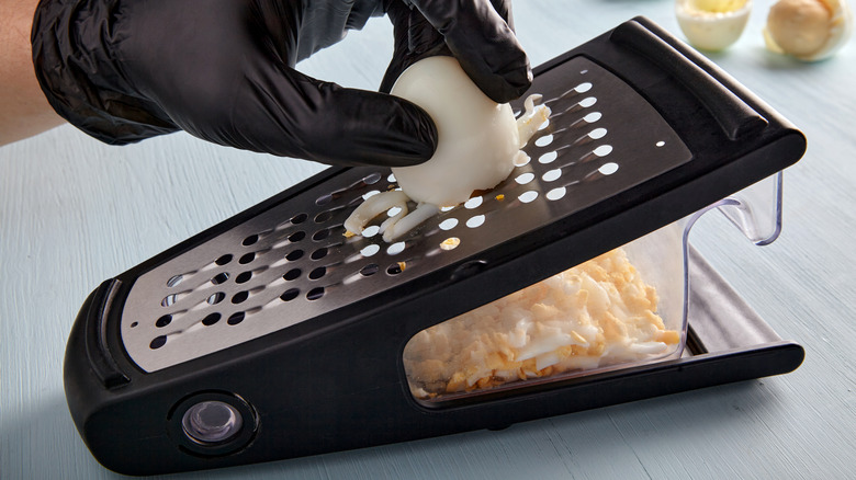 Pressing egg against cheese grater