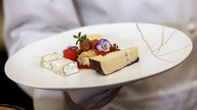 Waiter holding cheese plate with edible flowers