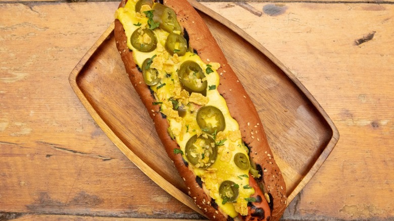 Overtop view of hot dog with nacho cheese, jalapenos, and crushed tortilla chips
