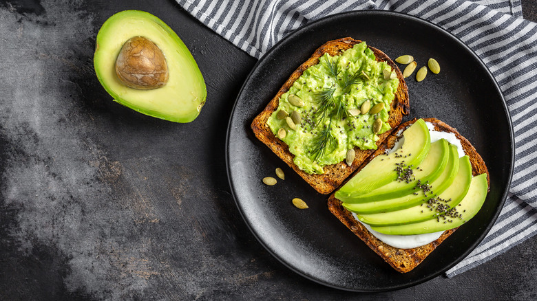 Sliced and mashed avocado on toast with half an avocado