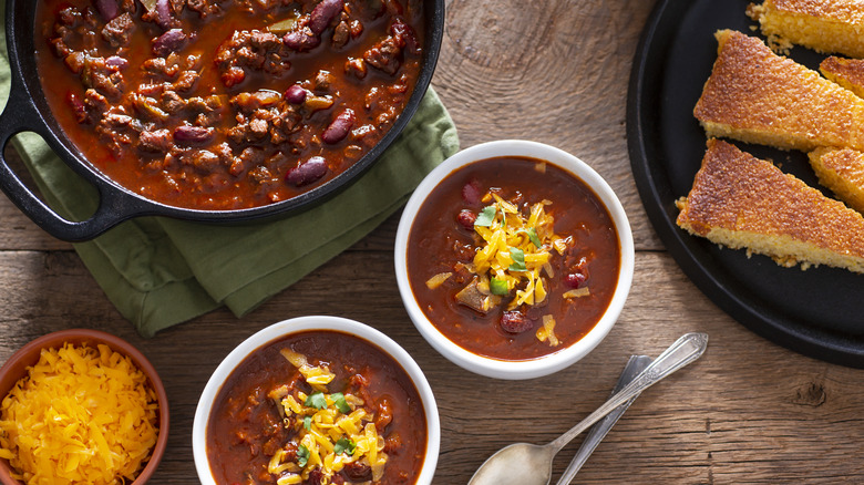 chili in a pot on table with two serving bowls