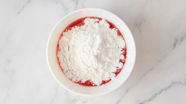 pink liquid and powdered sugar in a white bowl