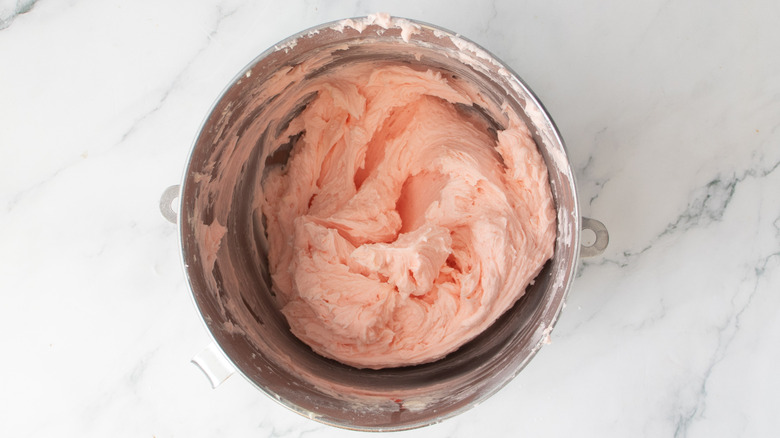 pink frosting in a metal bowl