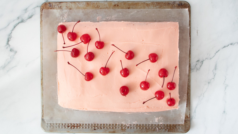pink-frosted cake with cherries on top