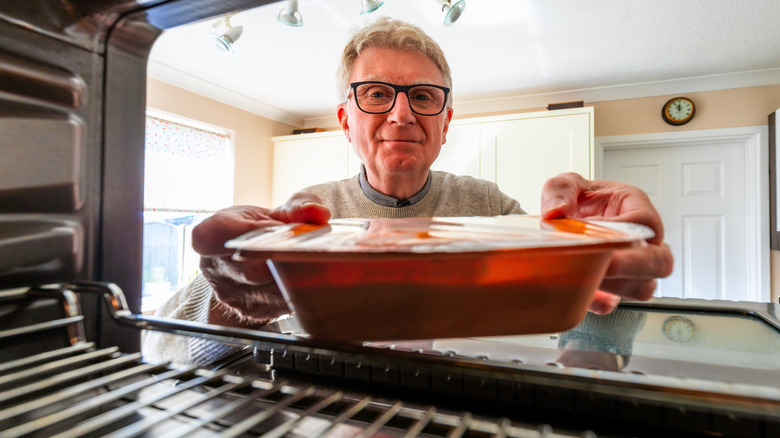 Person placing readymade food in oven
