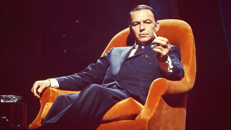 Frank Sinatra in an orange chair smoking a cigarette