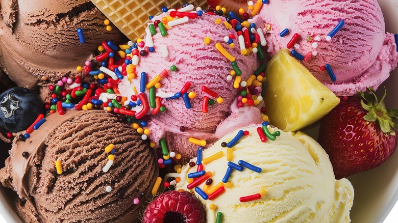 Top view of a bowl of ice cream with multiple flavors, sprinkles, and fruit
