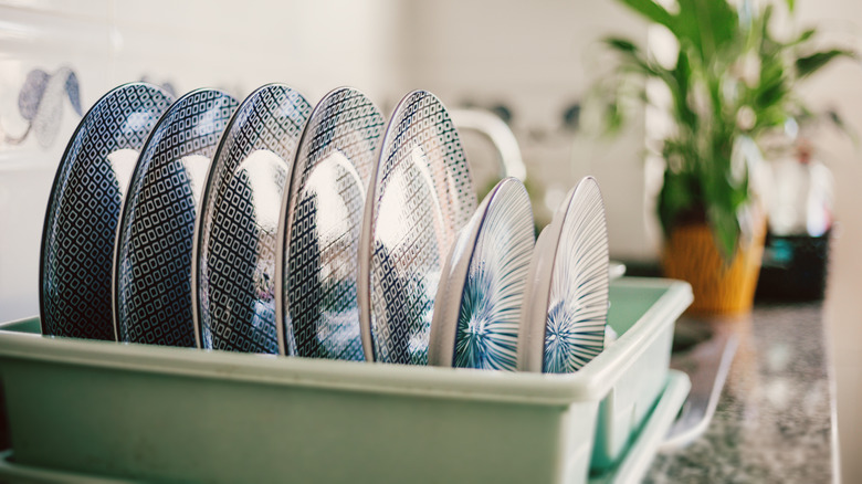 A countertop dish drying rack is filled with beautifully patterned plates