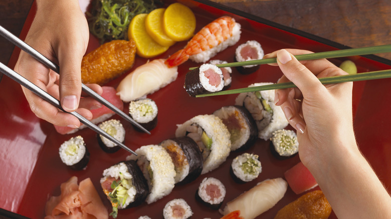 two diners eating sushi with chopsticks