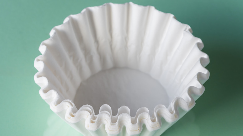 White disposable coffee filters sit against a green background