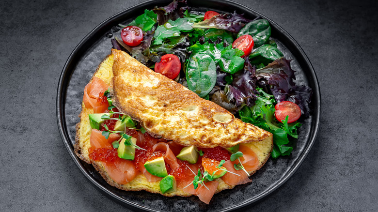 An omelet with smoked salmon, avocado, roe, and a dressed salad.