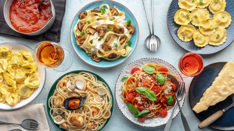 Various pasta, sauces, and wine with Parmesan wedge