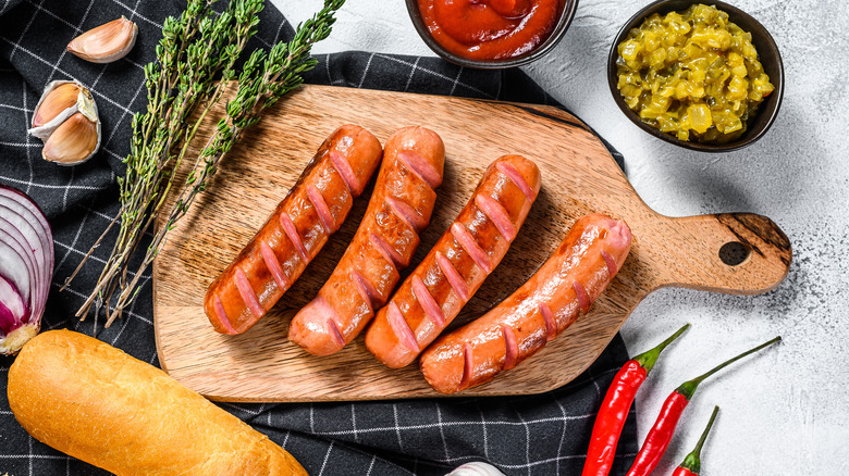 Ingredients for hot dogs on a wooden cutting board and table