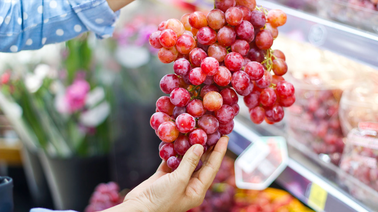 Shopper looking at a bunch of grapes