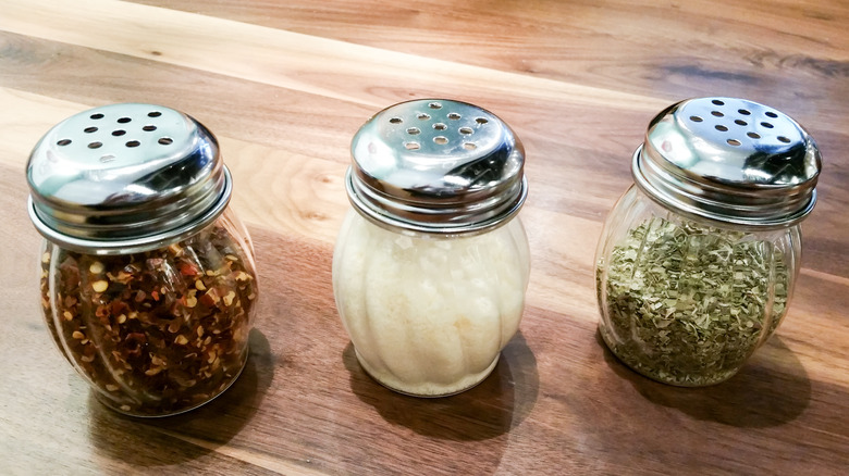Grated parmesan shaker between oregano and red chili flakes