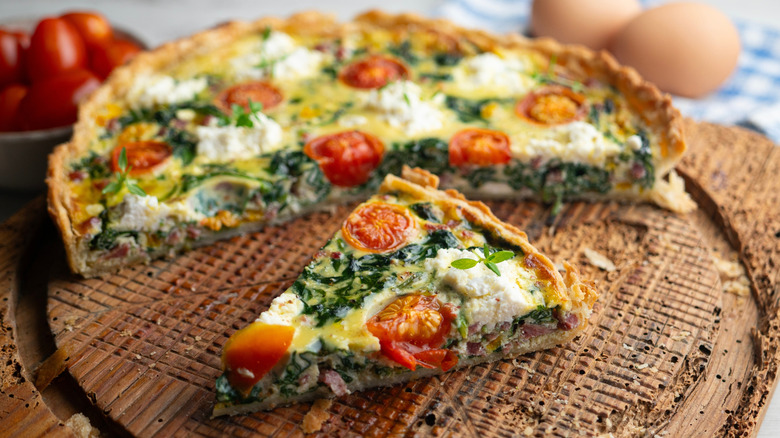 A breakfast quiche with spinach, tomatoes, and ham.