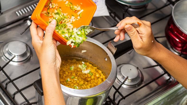 Adding chopped veggies to beans